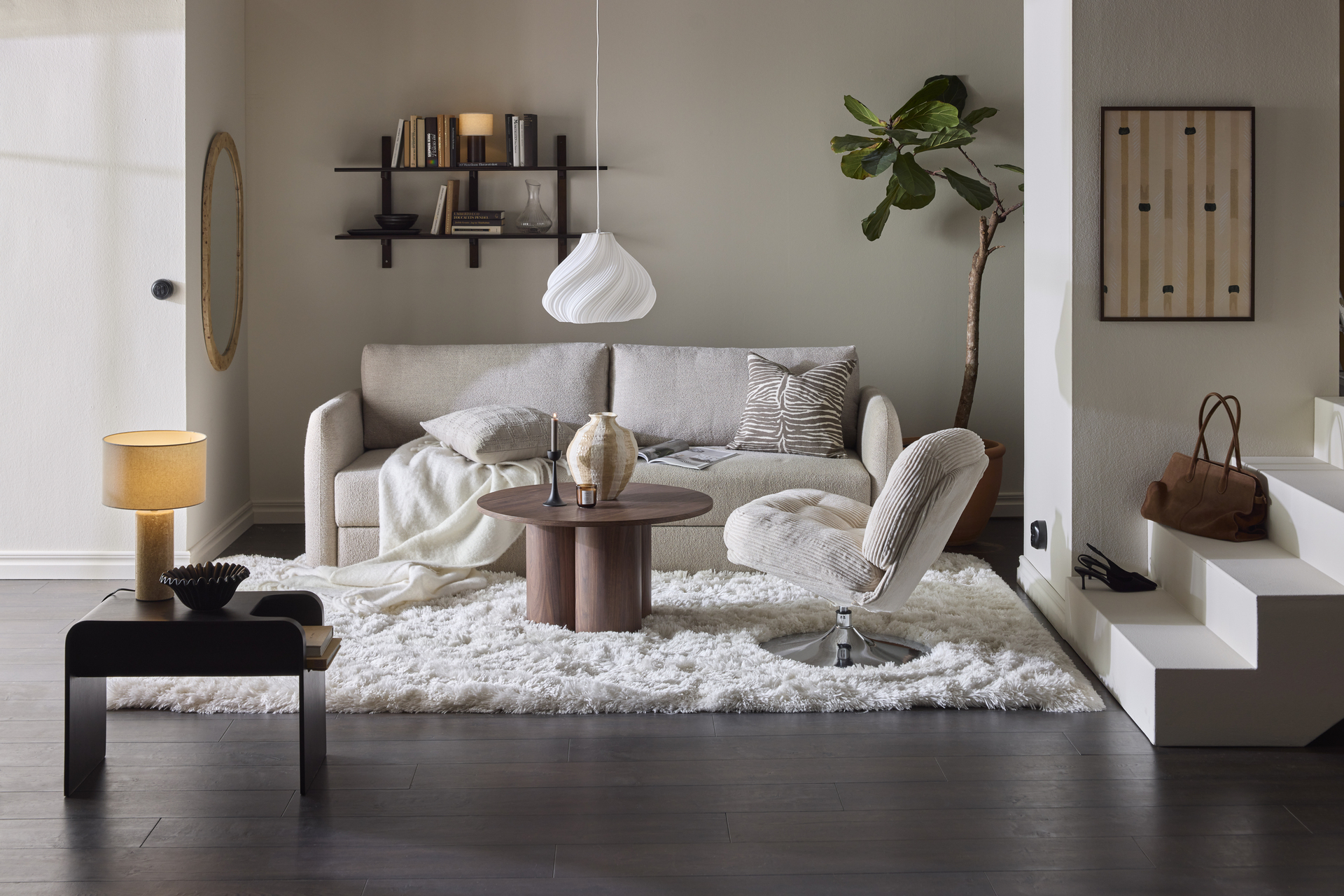 En beige soffa står i ett vardagsrum tillsammans med en vit matta och en beige fåtölj