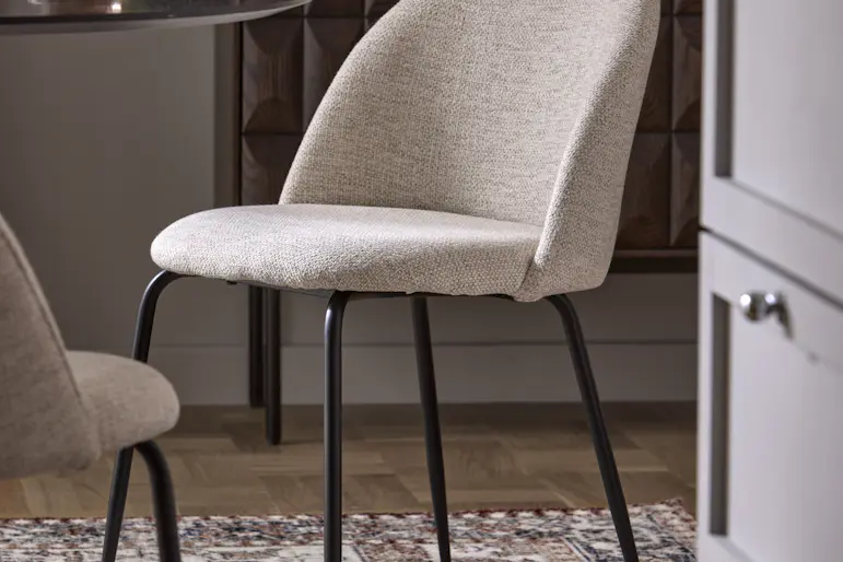 En stol med svart underrede och grå mjuk sits står i ett kök på en matta