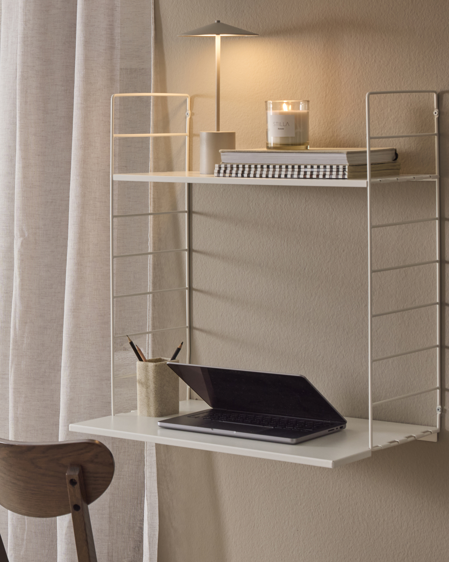 En vit hylla sitter på en beige vägg