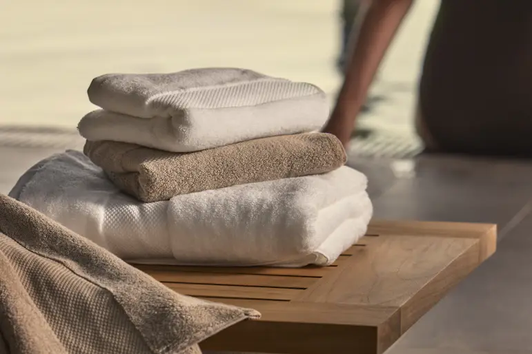 På en bänk vid ett spa ligger en hög med handdukar i olika färger