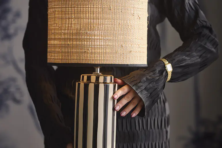 En randig bordslampa med en lampskärm i naturmaterial