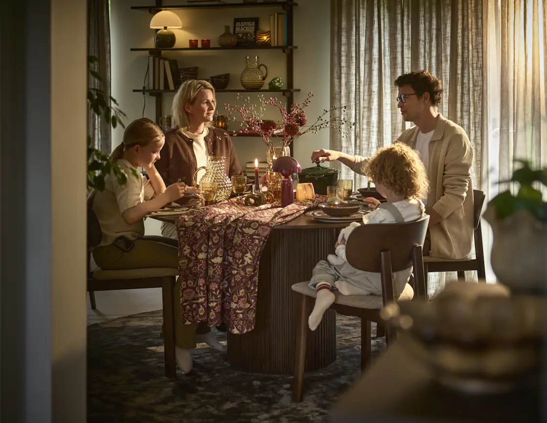 En familj sitter vid ett dukat höstigt bord och äter mat
