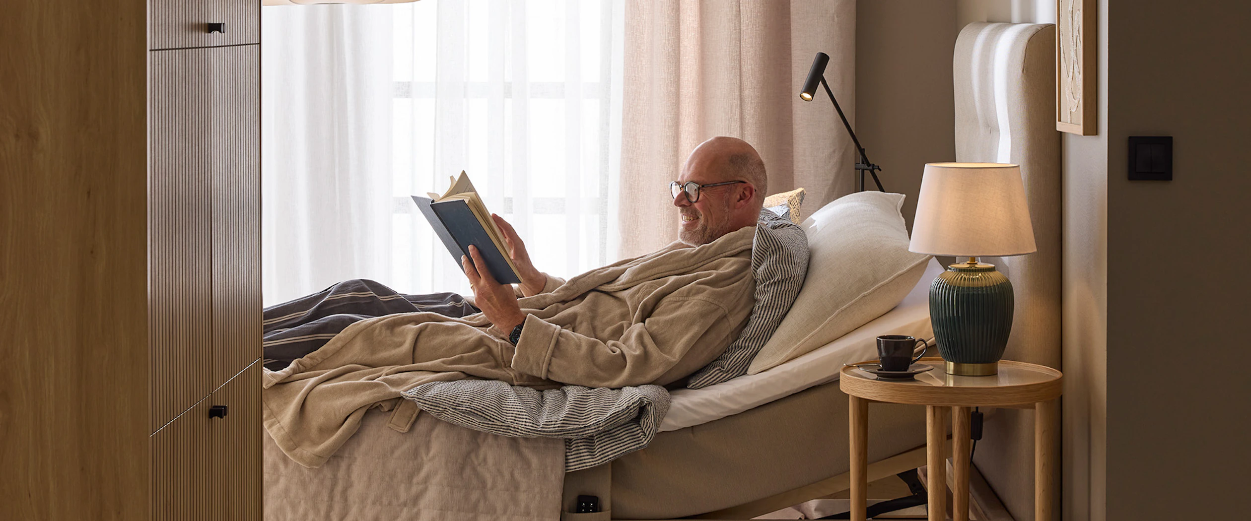 En man sitter i en ställbar säng och läser