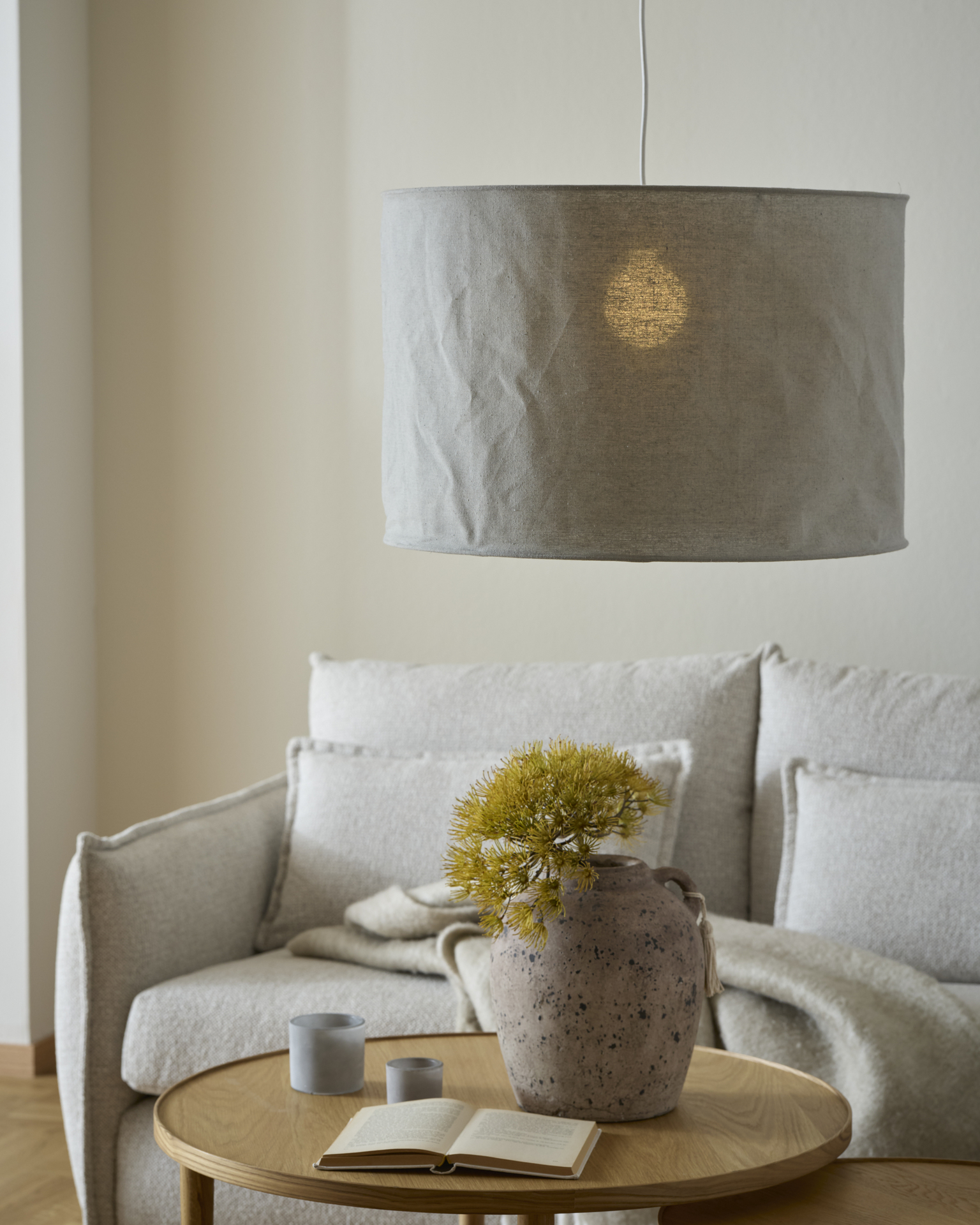En grå lampskärm hänger ner framför en soffa