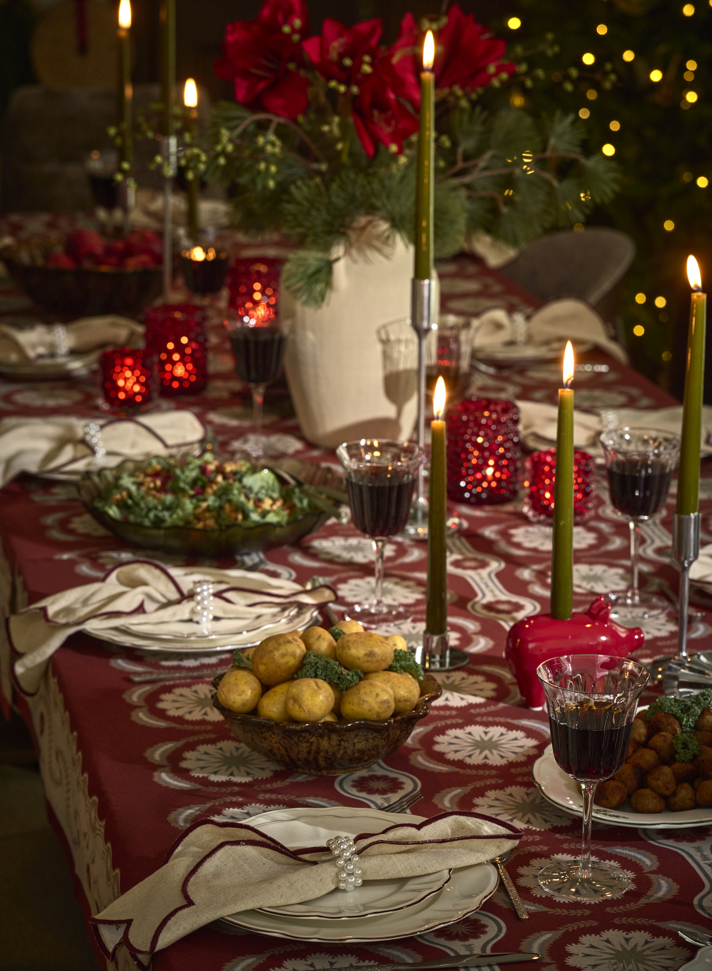 Ett juldukat matbord med glas och porslin, ljus samt blommor.