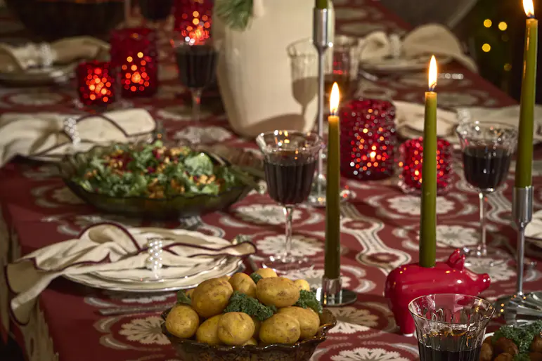 Ett juldukat matbord med glas och porslin, ljus samt blommor.