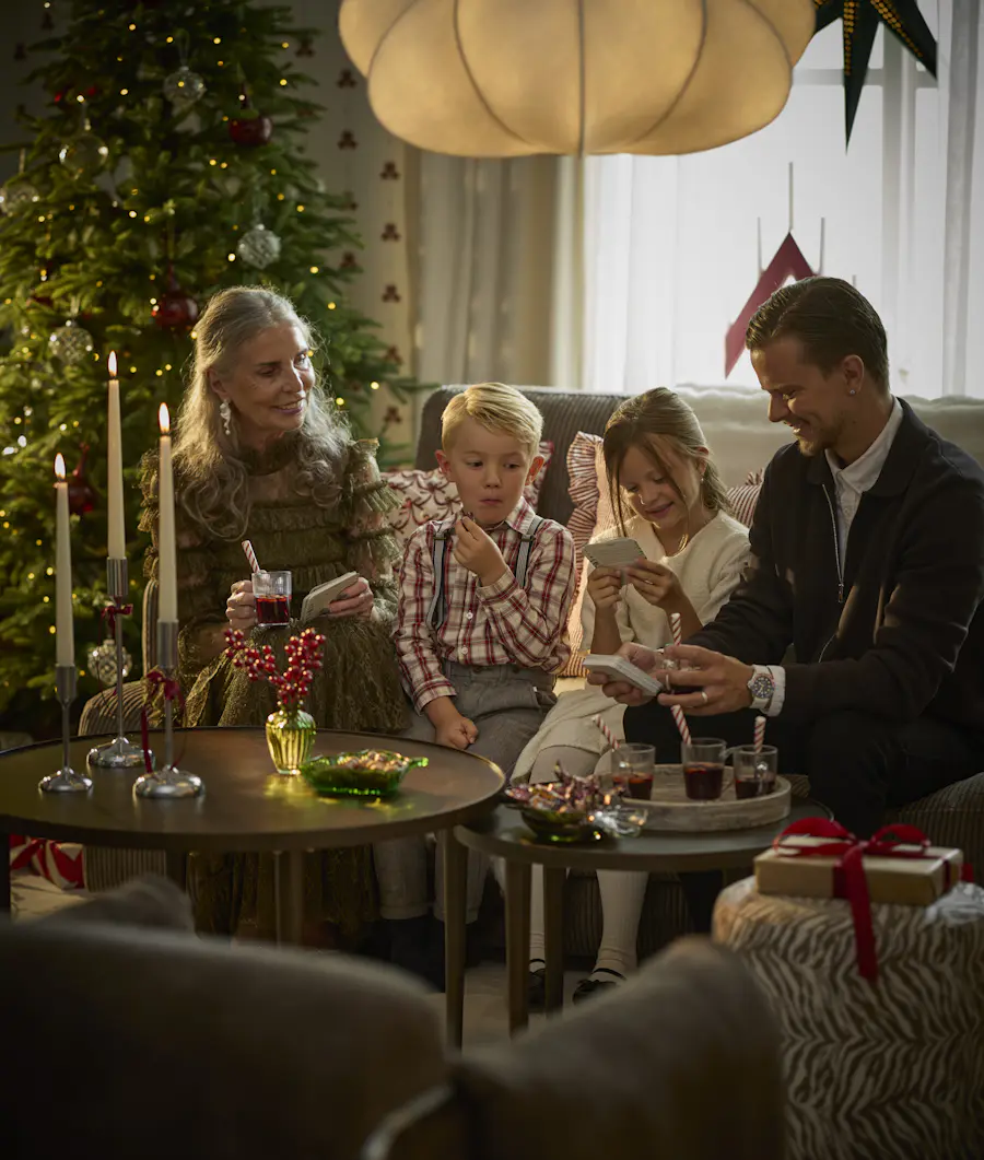 En familj sitter i en soffa och spelar kortspel
