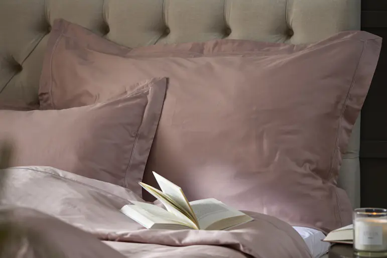 En beige kontinentalsäng bäddad med rosa påslakanset