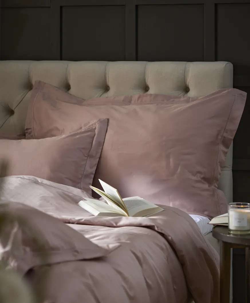 En beige kontinentalsäng bäddad med rosa påslakanset