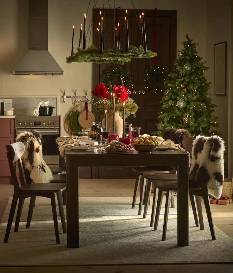 Julpyntad köksmiljö med ett mörkbrunt rektangulärt matbord och mörkbruna stolar sex stolar.
