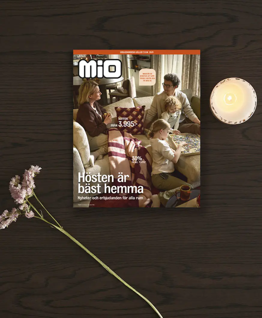Kampanjblad ligger på ett mörkt träbord tillsammans med en blomma och ett ljus.