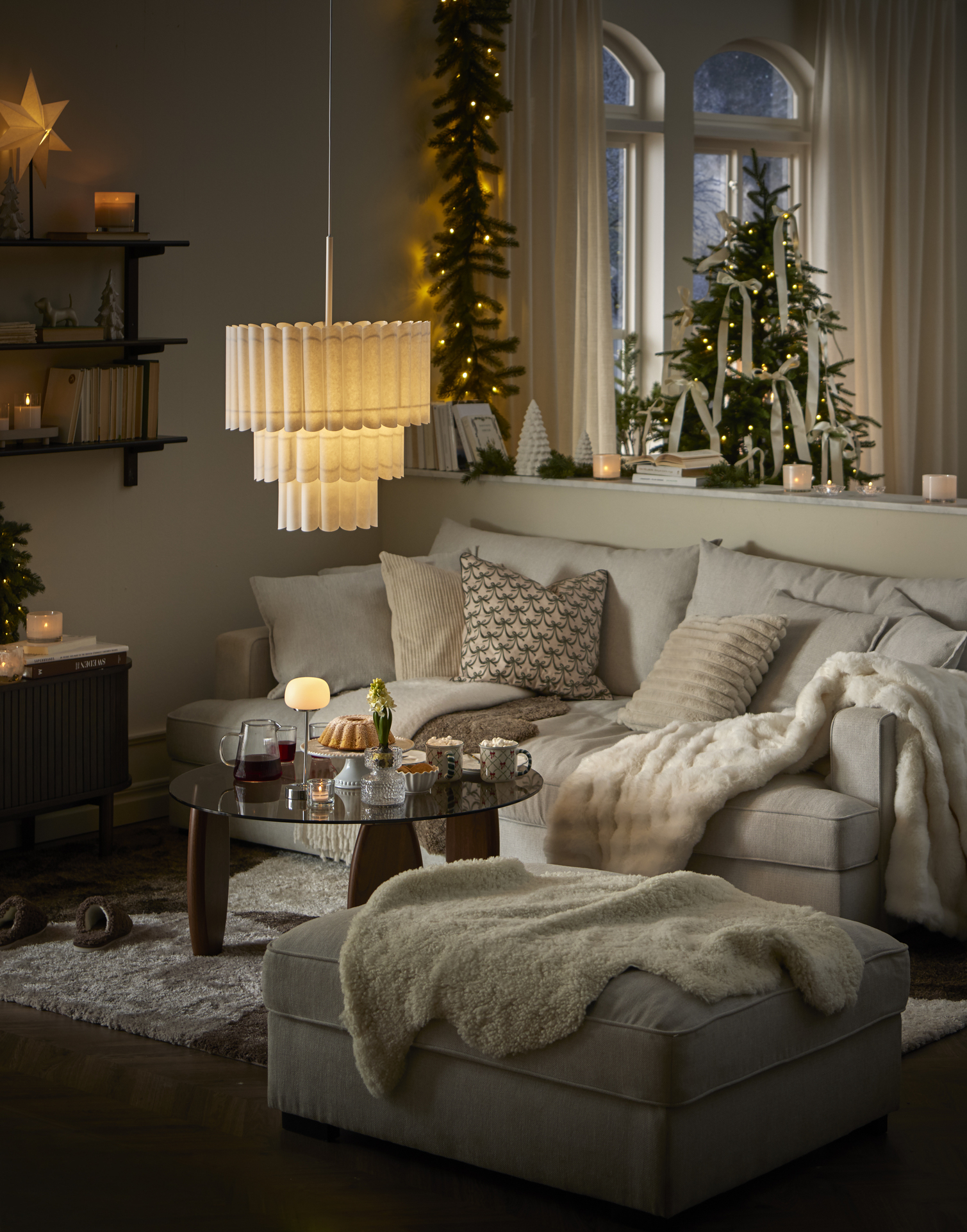 I ett ljust vardagsrum pyntat med gran, grangirlang och adventsbelysning står en ljus soffa.