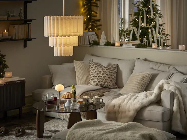 I ett ljust vardagsrum pyntat med gran, grangirlang och adventsbelysning står en ljus soffa.
