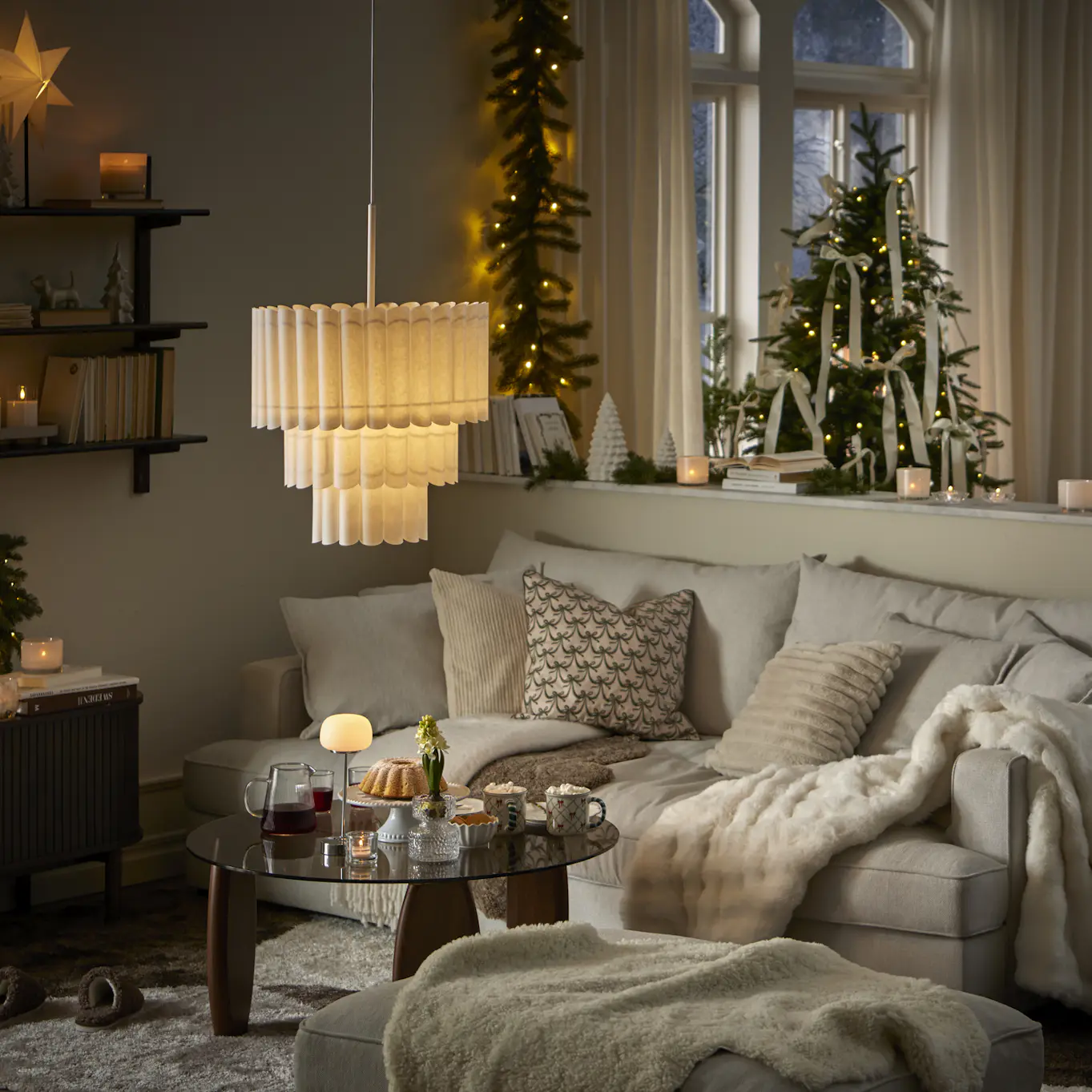 I ett ljust vardagsrum pyntat med gran, grangirlang och adventsbelysning står en ljus soffa.
