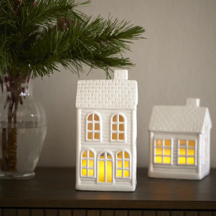 En ljuslykta i form av ett hus står på en bänk