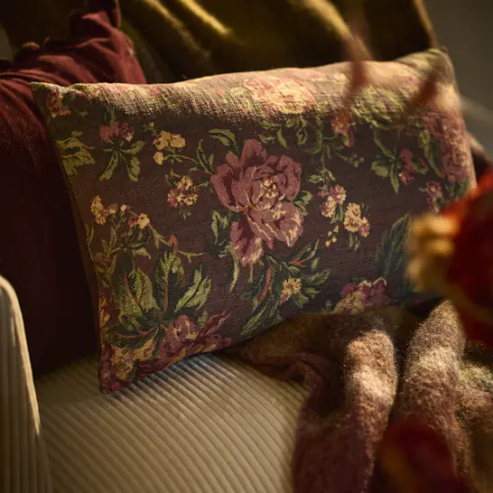 En brun prydnadskudde med blommönster ligger på en beige soffa