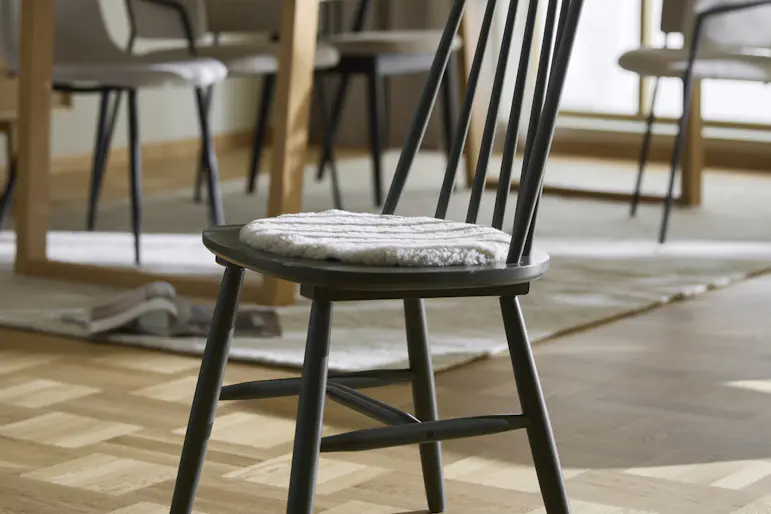 Grönlackerad stol med ribbor och grå stolsdyna står framför ett bord.