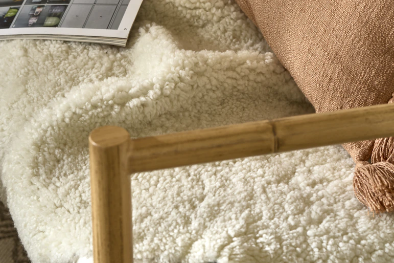 På en soffa ligger ett vitt fårskinn, en rosa kudde och ett uppslaget magasin.