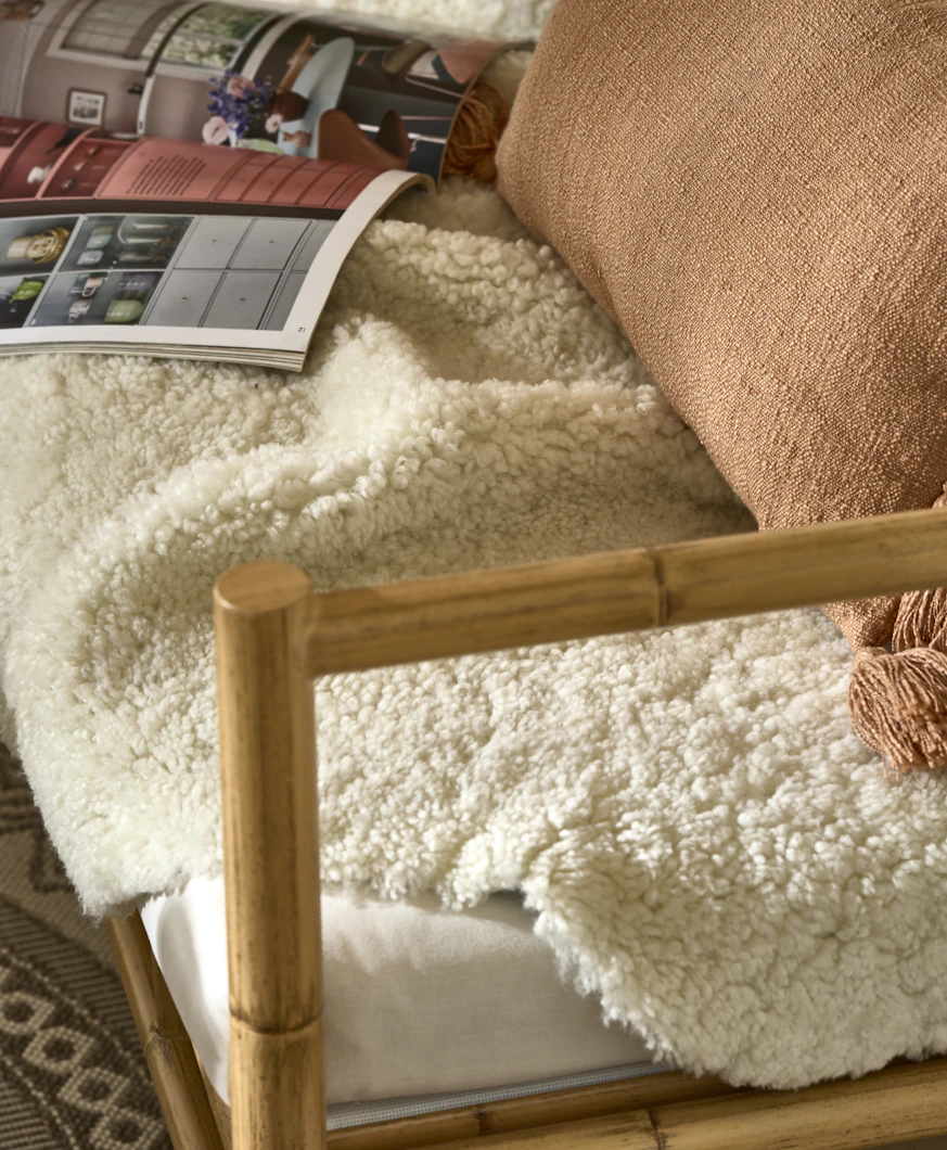 På en soffa ligger ett vitt fårskinn, en rosa kudde och ett uppslaget magasin.