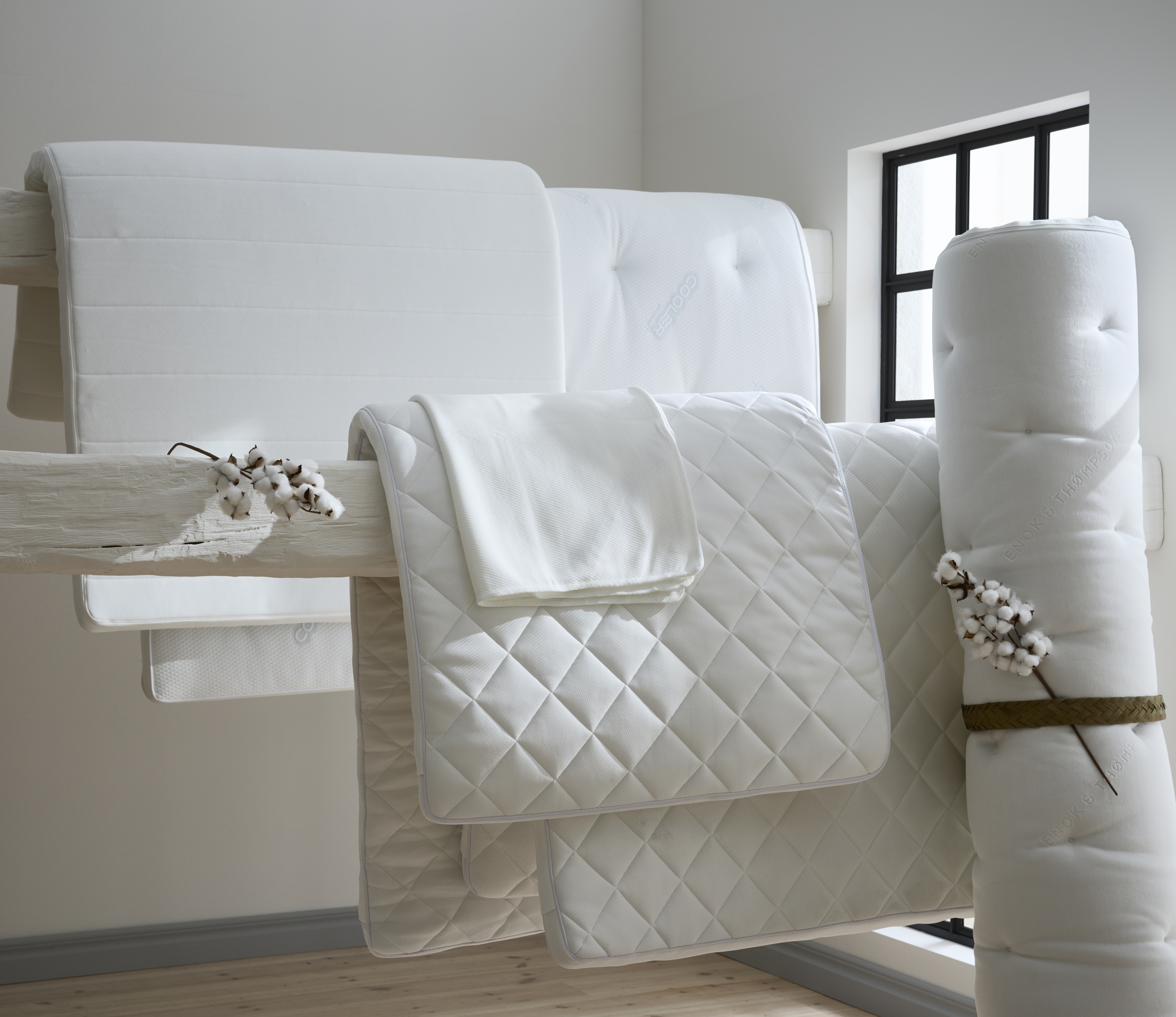 olika vita bäddmadrasser som hänger och står i ett rum