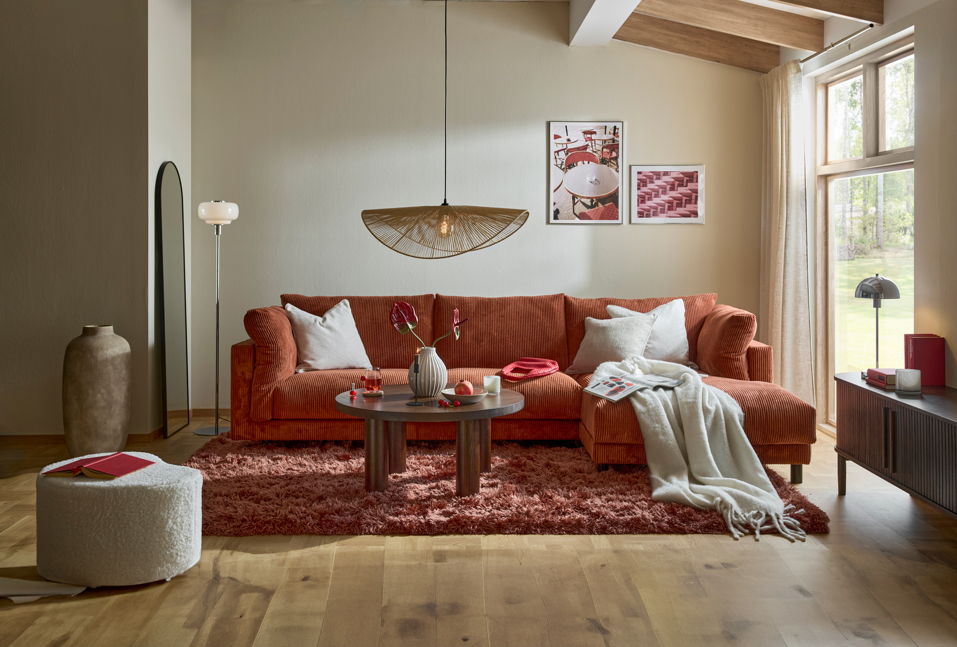 I ett vardagsrum står en rostfärgad Cherrie i manchester bredvid ett stort fönster