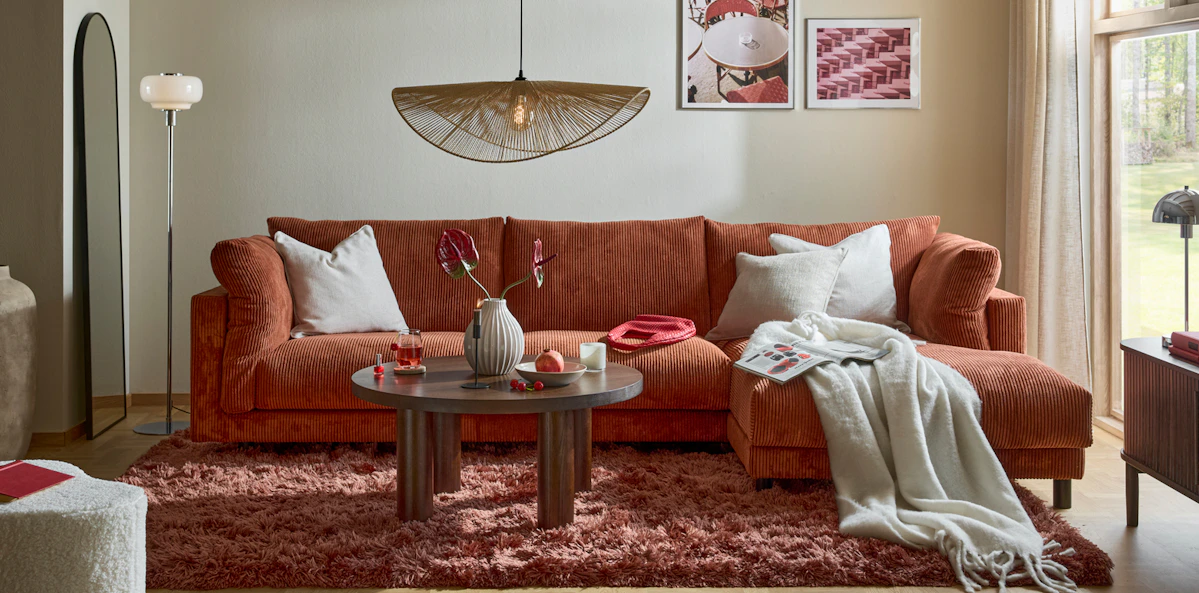 I ett vardagsrum står en rostfärgad Cherrie i manchester bredvid ett stort fönster