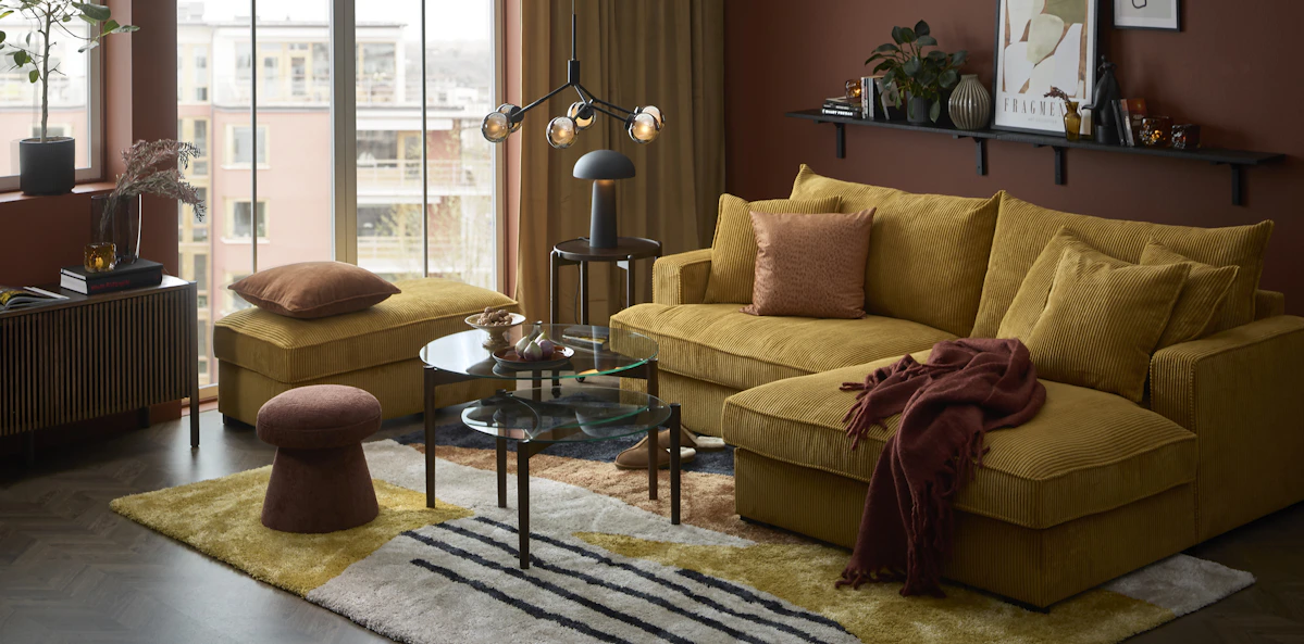 I ett murrigt vardagsrum står en senapsgul Mila soffa i manchester