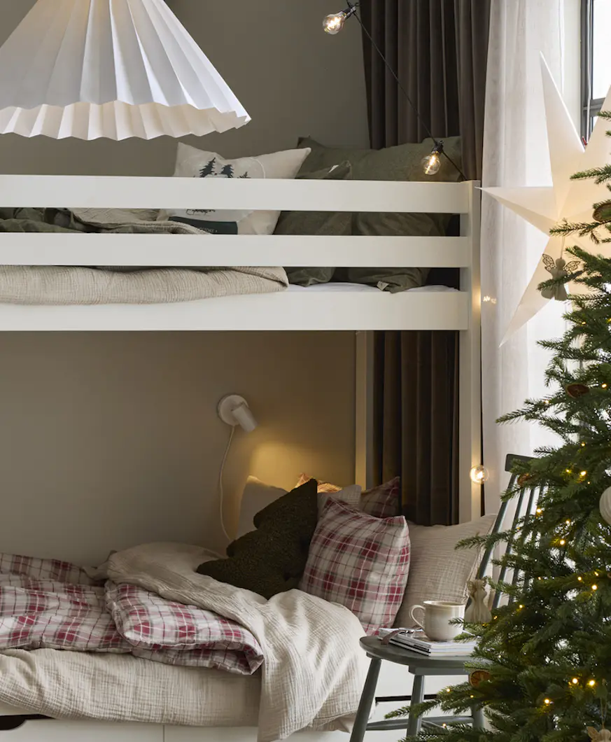 I ett sovrum står en bäddad vit våningssäng. Intill står en julgran och i fönstret hänger en julstjärna.
