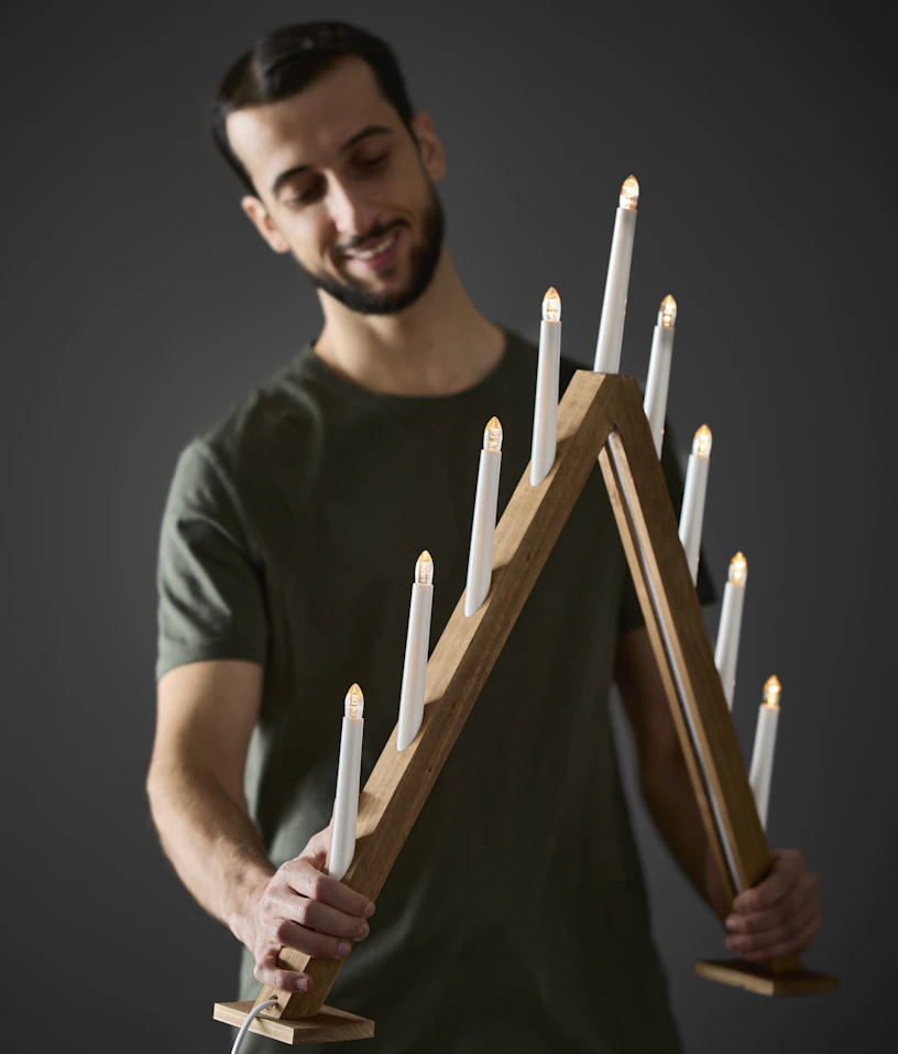 En man håller upp en adventsljusstake i trä