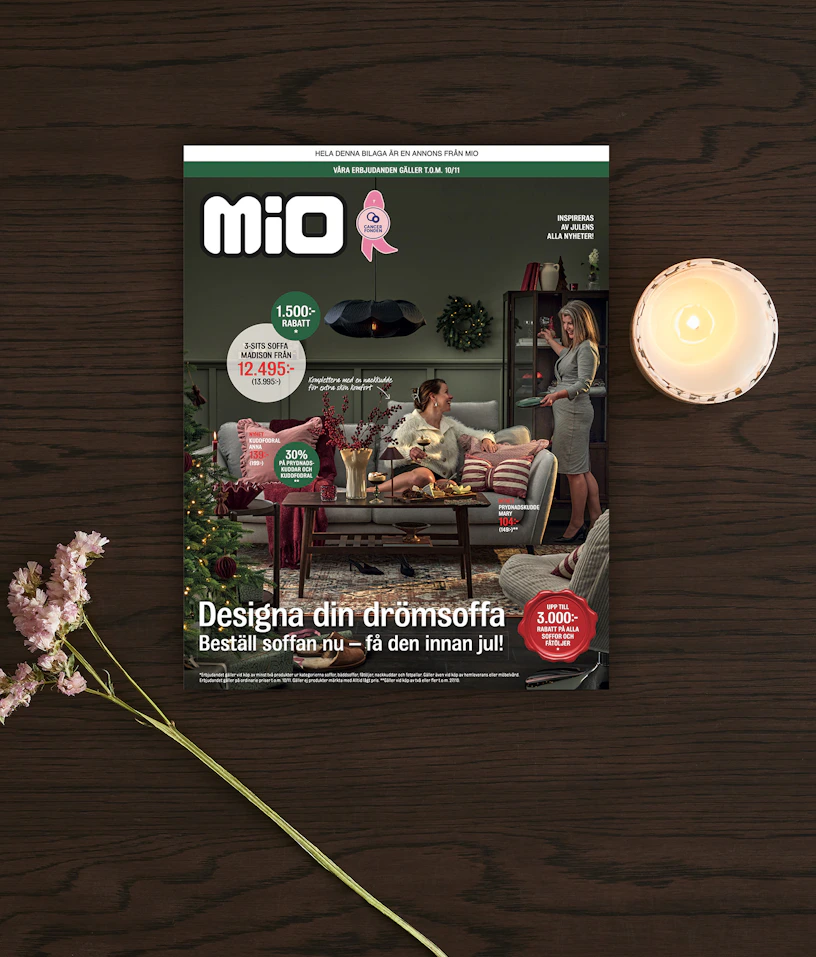 ett kampanjblad liggandes på ett bord med ett ljus och en blomma bredvid