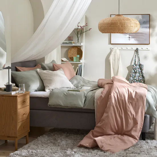 Ramsäng i modernt sovrum med sänghimmel och textilier i ljusa rosa färger. 