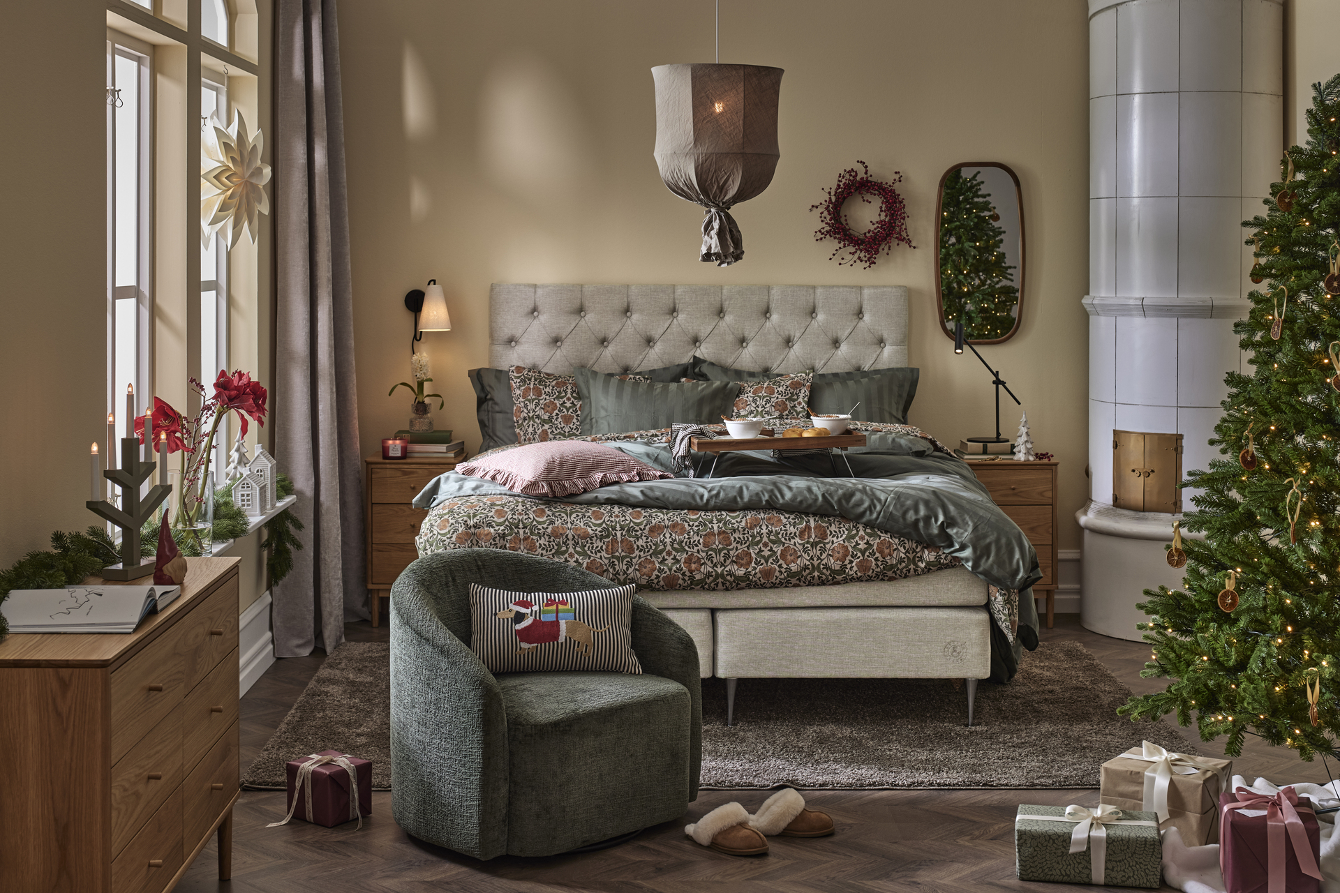 ett sovrum med en stor beige säng, en taklampa i tyg och en vit kakelugn i hörnet av rummet