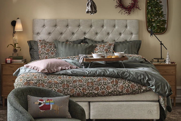 ett sovrum med en beige säng, en kakelugn och en julgran