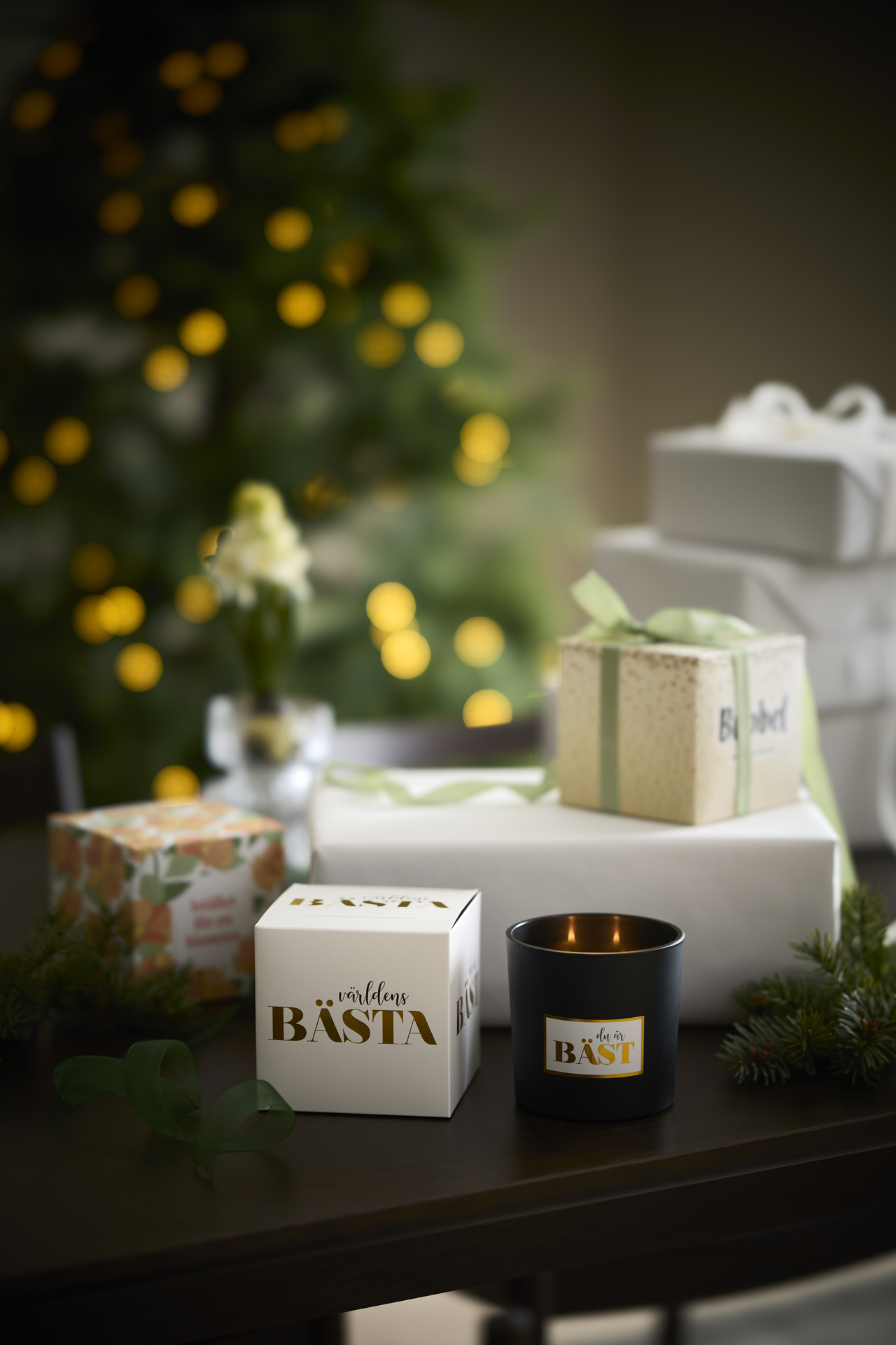 doftljus med olika förpackningar ståendes på ett bord framför en gran