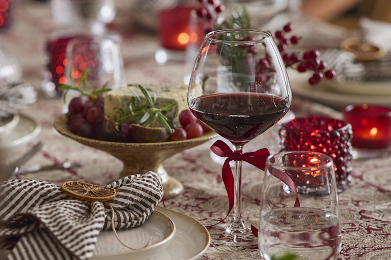 ett dukat julbord med ett vinglas i fokus