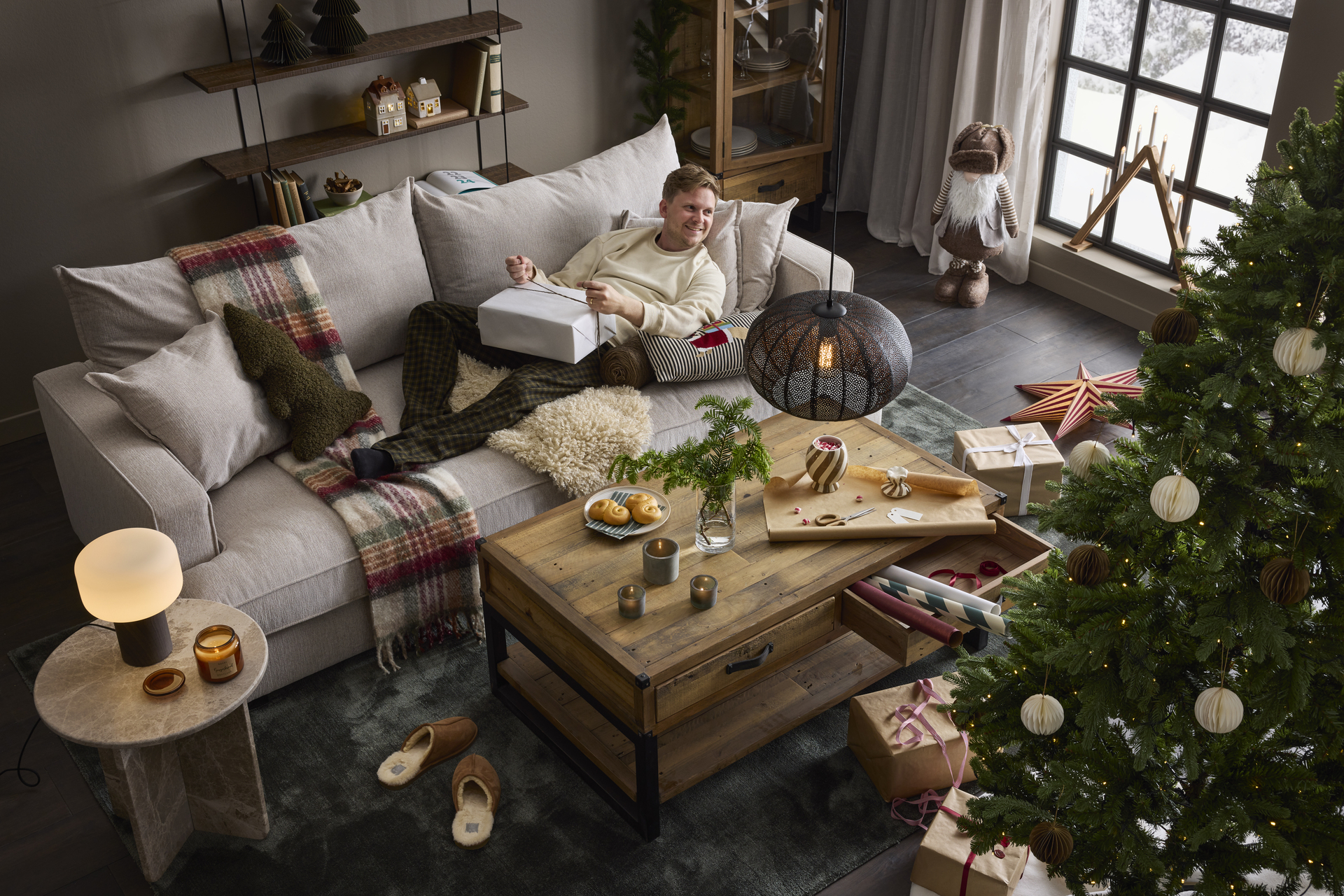 en kille liggandes på en stor grå soffa och håller i en julklapp