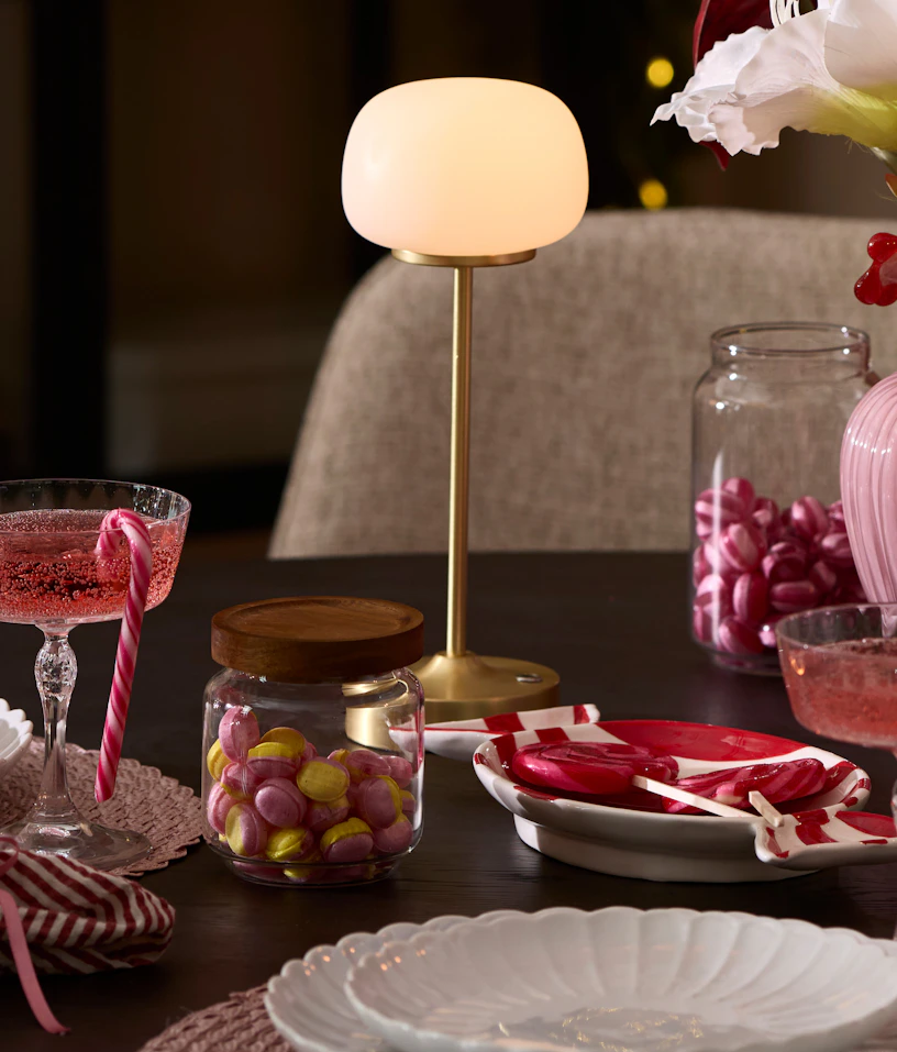 ett dukat bord med en guldig och vit portabel lampa i fokus