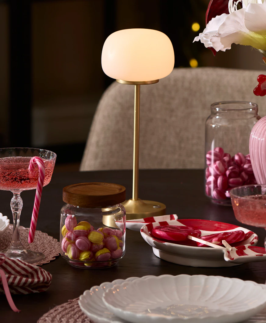 ett dukat bord med en guldig och vit portabel lampa i fokus