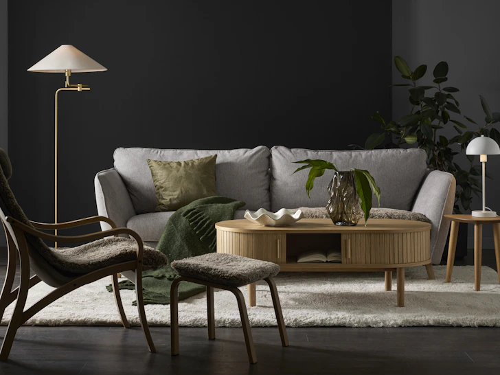 En ljusgrå soffa i klassisk design står i ett mörkt rum