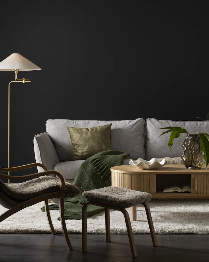 En ljusgrå soffa i klassisk design står i ett mörkt rum