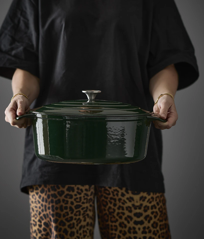 En person håller i en mörkgrön gjutjärnsgryta