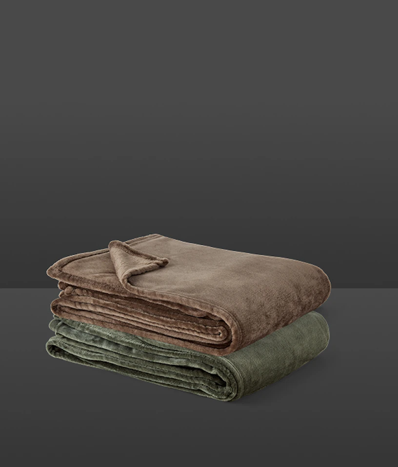 Två prydligt hopvikta plädar i grönt och rost ligger på varandra