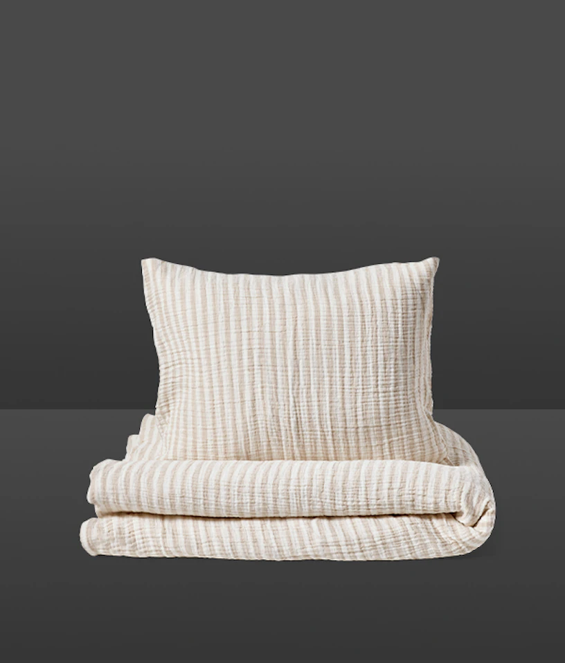 Ett påslakanset med randigt mönster i beige och vitt