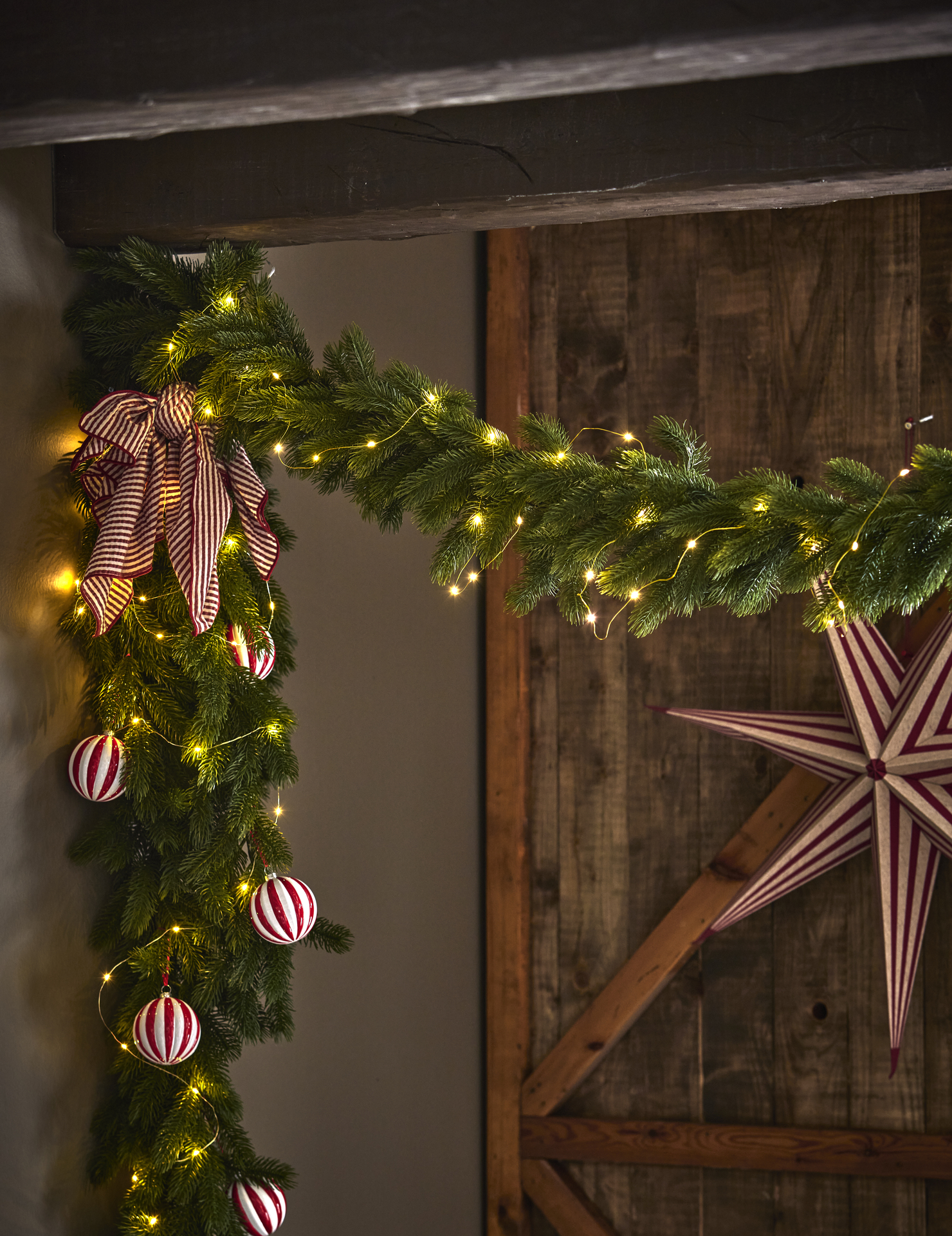 en grangirlang med en ljusslinga och en röd julstjärna i bakgrunden