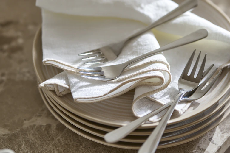 bestick liggandes på en hög med tallrikar