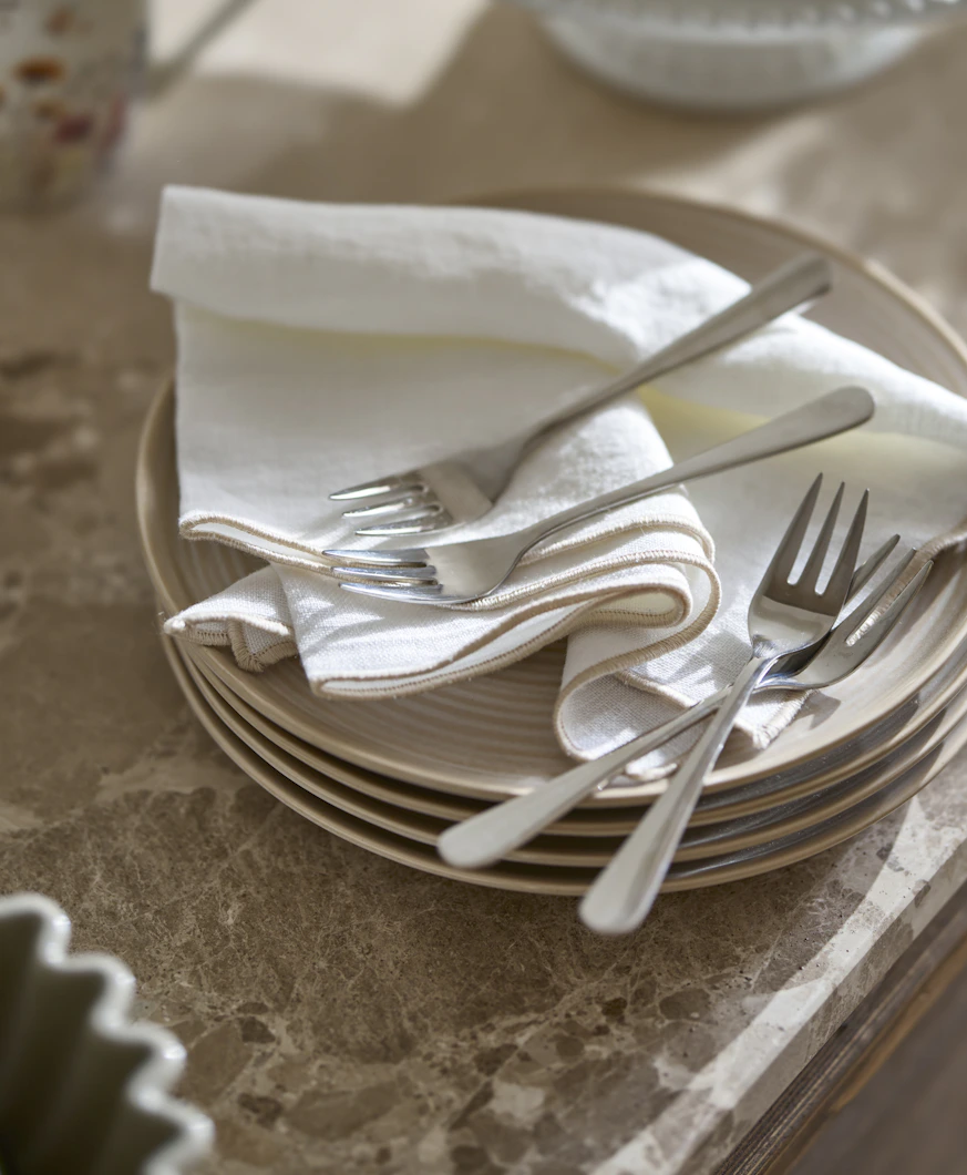 bestick liggandes på en hög med tallrikar