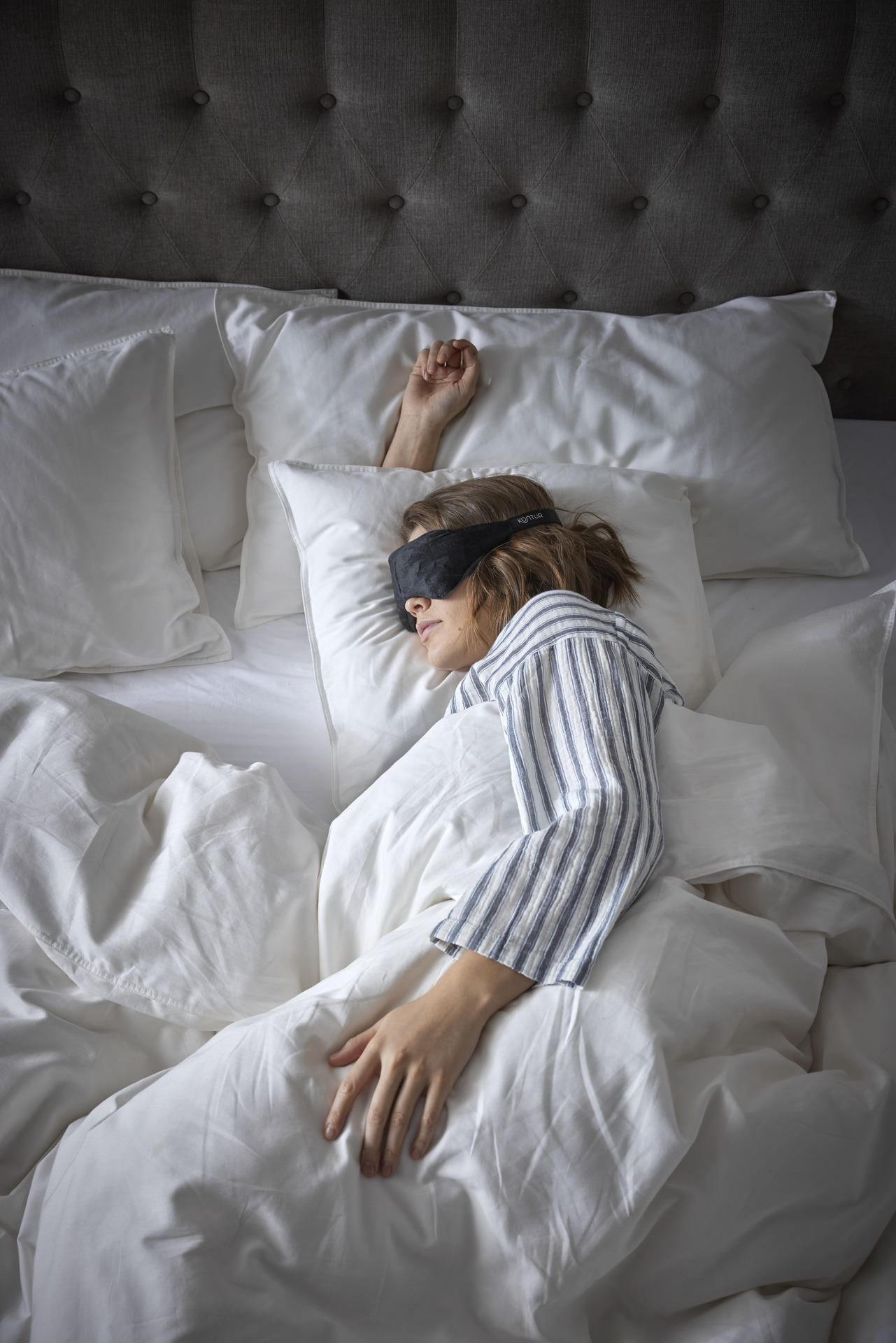 en tjej sovandes i en säng med sovmask över ögonen