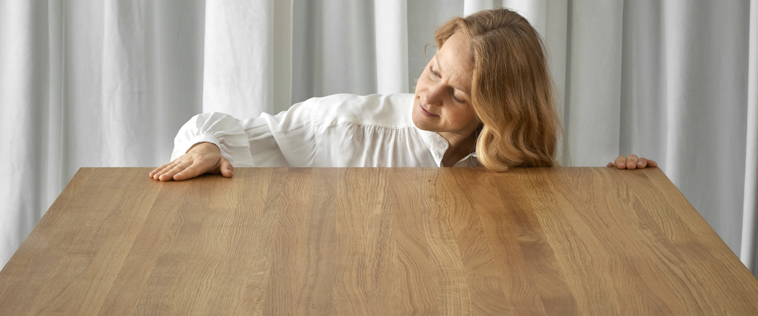 Kvinna stryker handen över en matbordsyta.