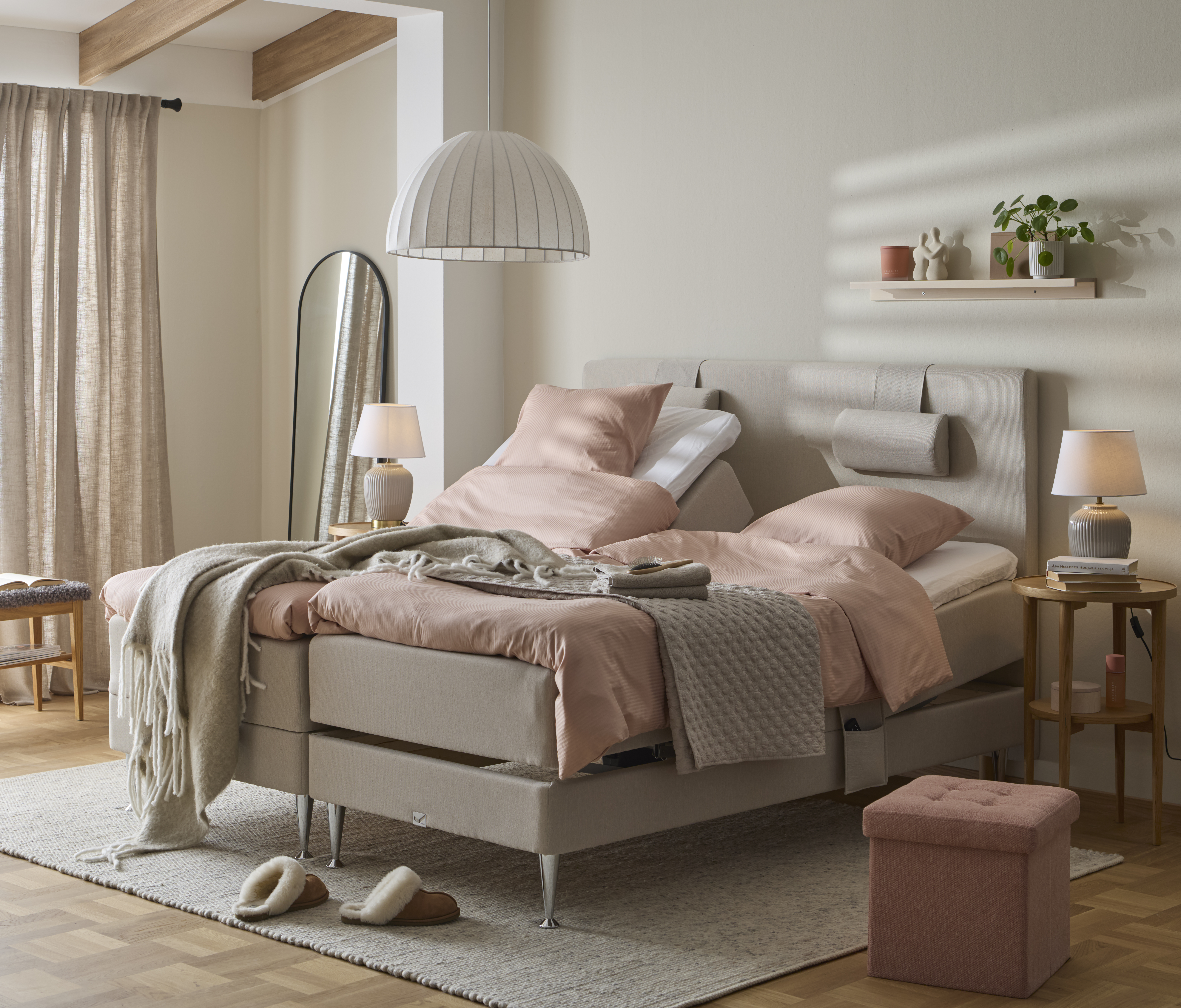 ett grått överkast ligger på en beige säng med rosa sängkläder