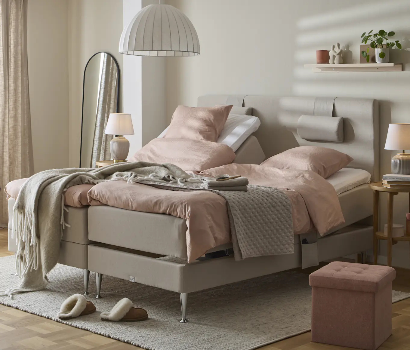en beige ställbar säng bäddad med rosa påslakan står i ett ljust sovrum